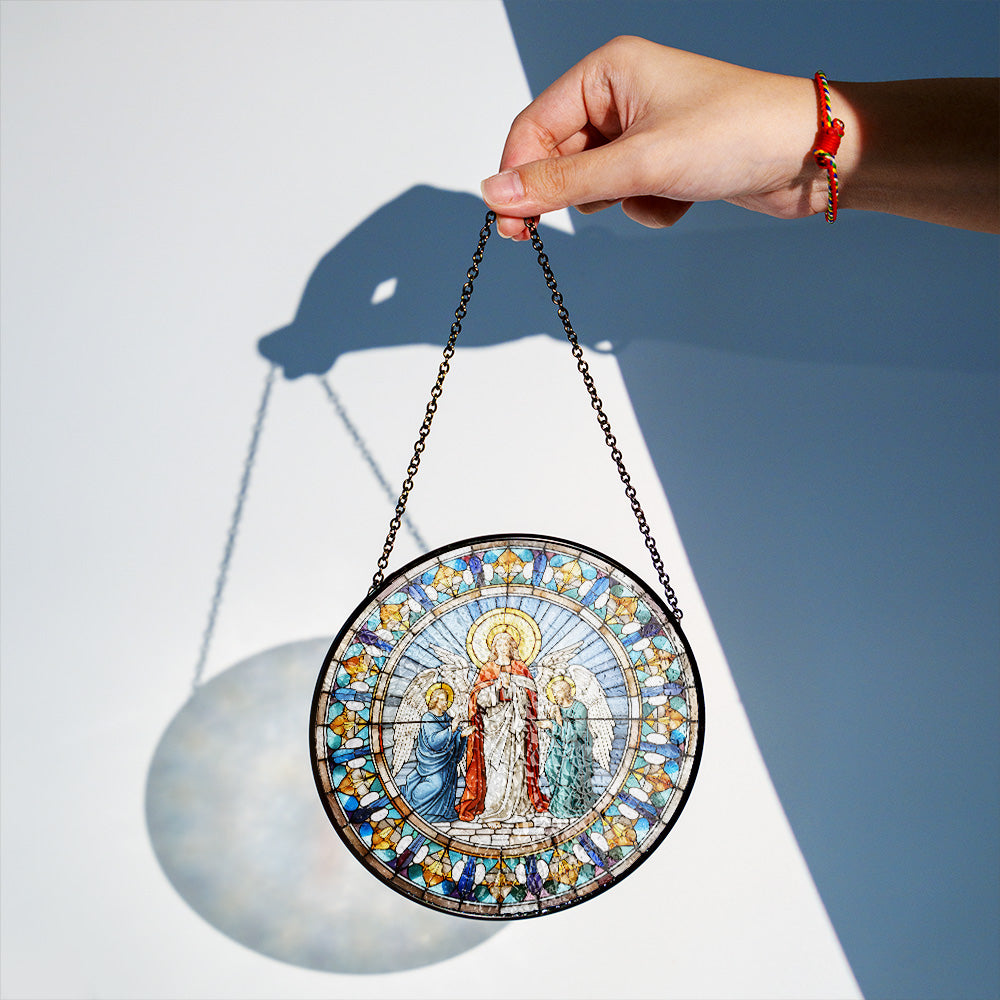 Virgin Mary stained glass suncatcher displayed as religious window decor. The ornament features a religious scene with mother Mary as a  robed figure and surrounding blue, gold, and white decorative panels.