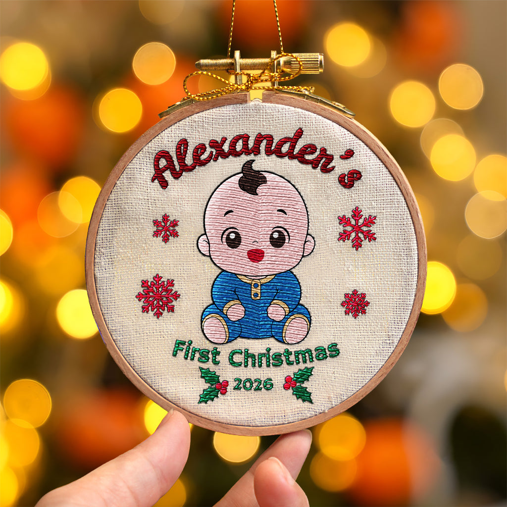 Personalized baby first Christmas embroidered hoop ornament showing smiling baby, red snowflakes and holly with gold metallic hanger