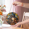 Halloween witch suncatcher with long flowing hair and colorful details held by a hand in front of a window