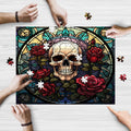 A puzzle with a stained glass art design featuring a skull and roses, being assembled by people using pieces with a wooden texture.
