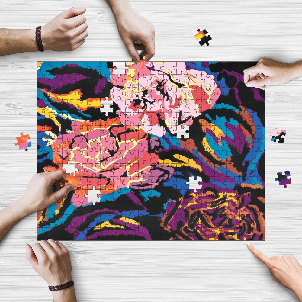 A colorful wooden jigsaw puzzle with a floral pattern, held by hands against a white background.